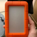 Dettaglio ravvicinato dell'hard disk LaCie Rugged tenuto in mano, ideale se cerchi un hard disk esterno quale scegliere per resistere agli urti.