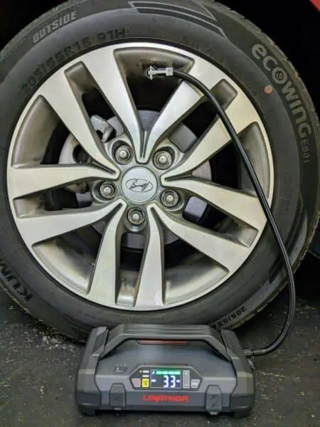 Lokithor JA301 utilizzato come compressore portatile per gonfiare lo pneumatico di un'auto, con display acceso su 33 PSI.