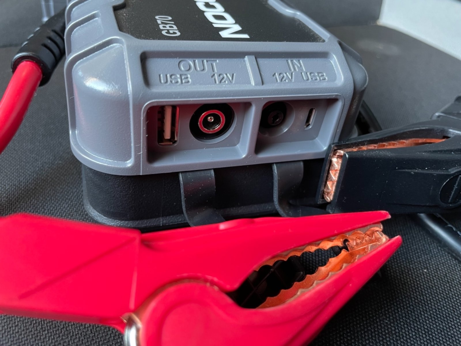 Dettaglio delle porte di ricarica USB e 12V IN/OUT del booster auto NOCO Boost HD GB70 con pinza rossa antiscintilla.